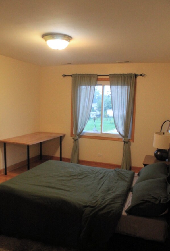A room with a bed, a table, and a window with curtains.