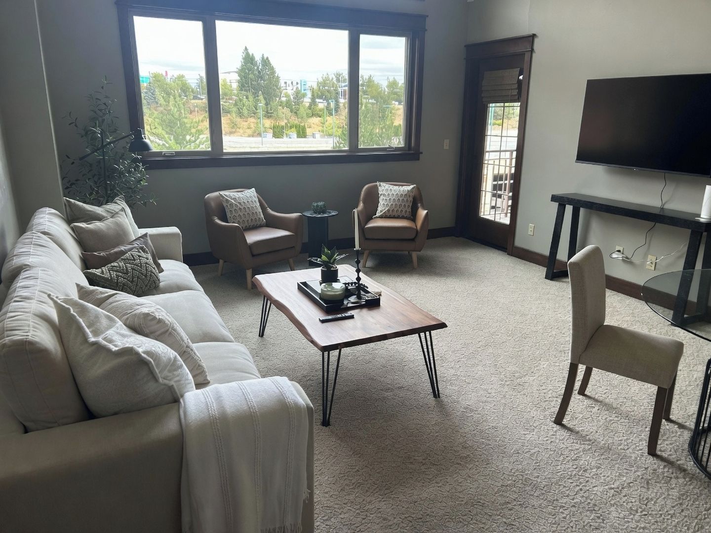 A living room with a sofa, two armchairs, a coffee table, and a TV.