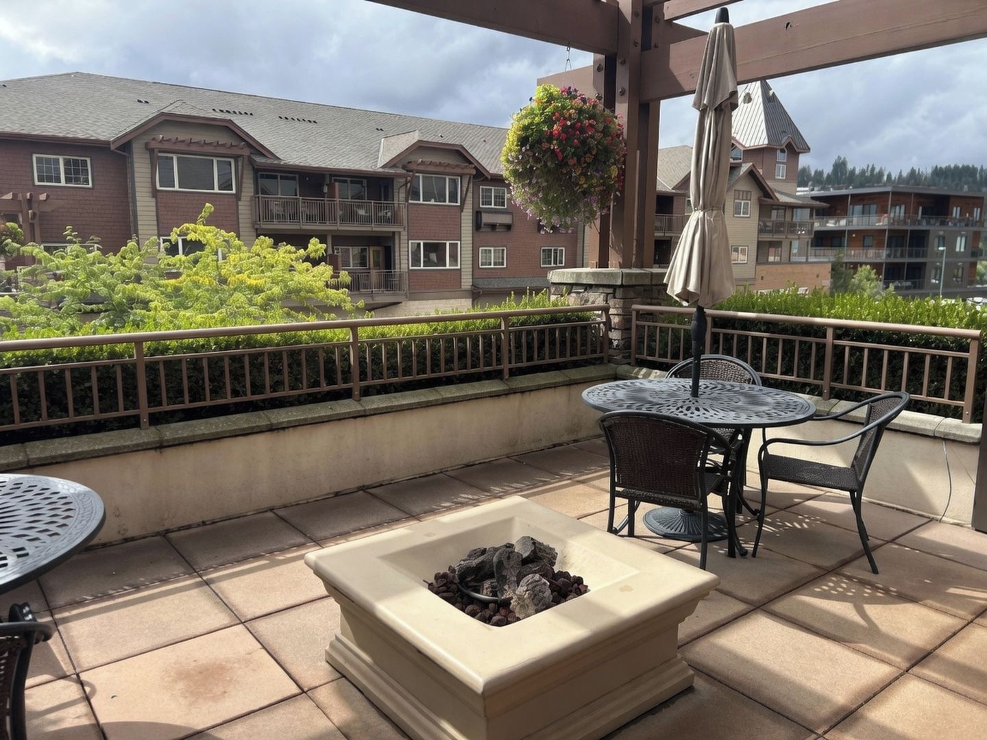 A patio area with a fire pit, outdoor furniture, and a hanging flower basket.