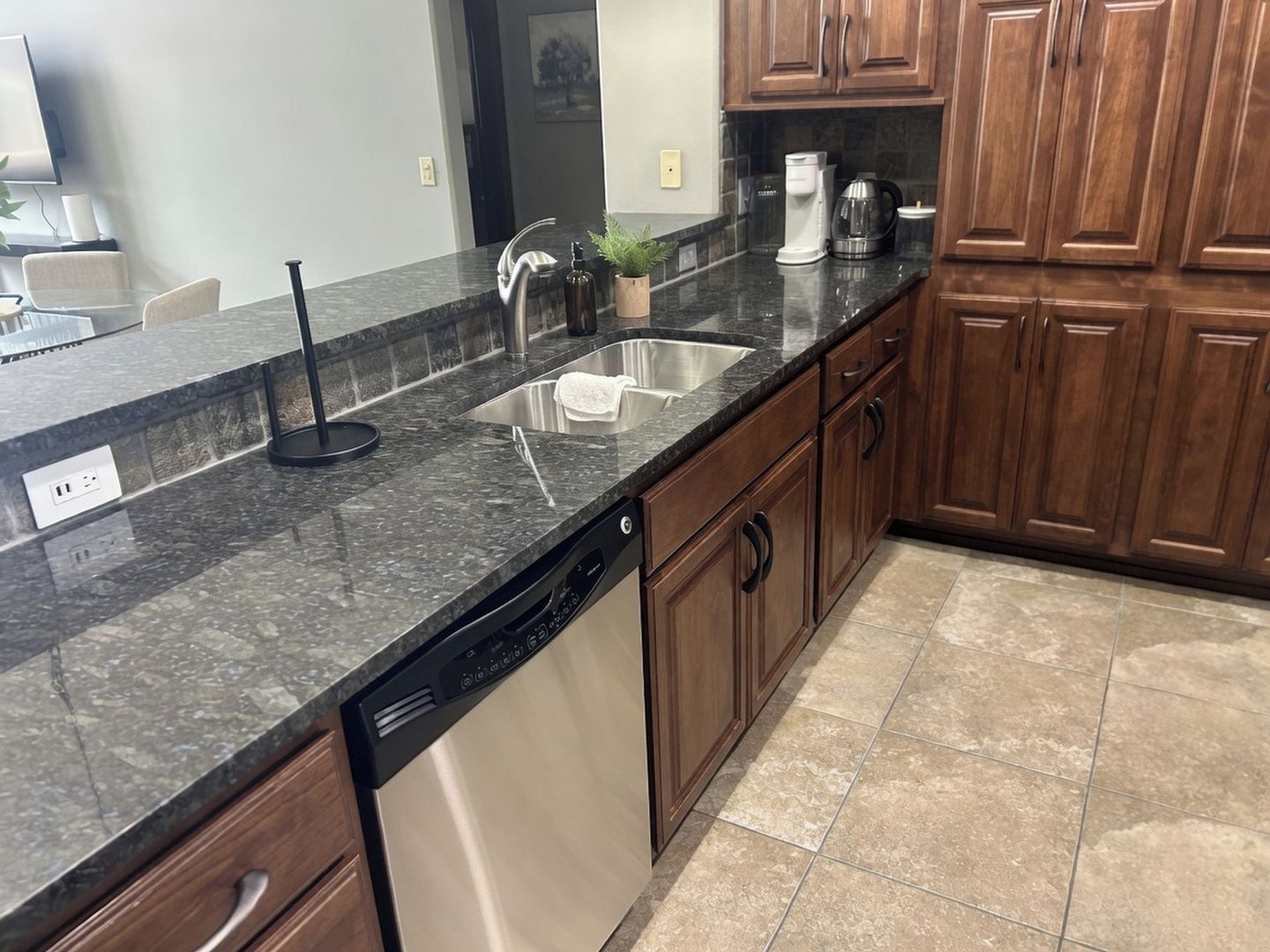 A kitchen with a dishwasher, a sink, and wooden cabinets.