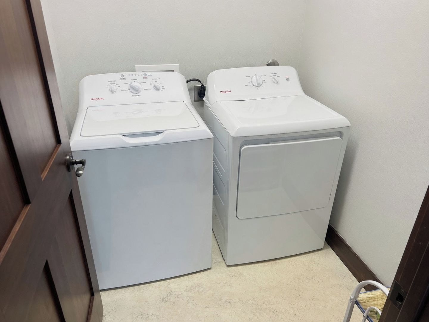 A laundry room with two front-loading washing machines and a dryer.