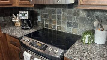 A kitchen with a stainless steel microwave, a coffee maker, and a granite countertop.