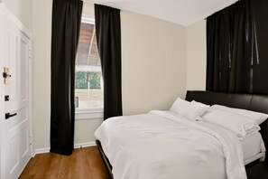 A bedroom with a bed, a window with curtains, a door, and a view of the outdoors. - Bright & Spacious Home Near Downtown Indy (Indianapolis)