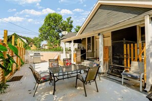 An outdoor patio with a glass table and chairs, a barbecue grill, and a covered area with a wooden fence. - Bright & Spacious Home Near Downtown Indy (Indianapolis)