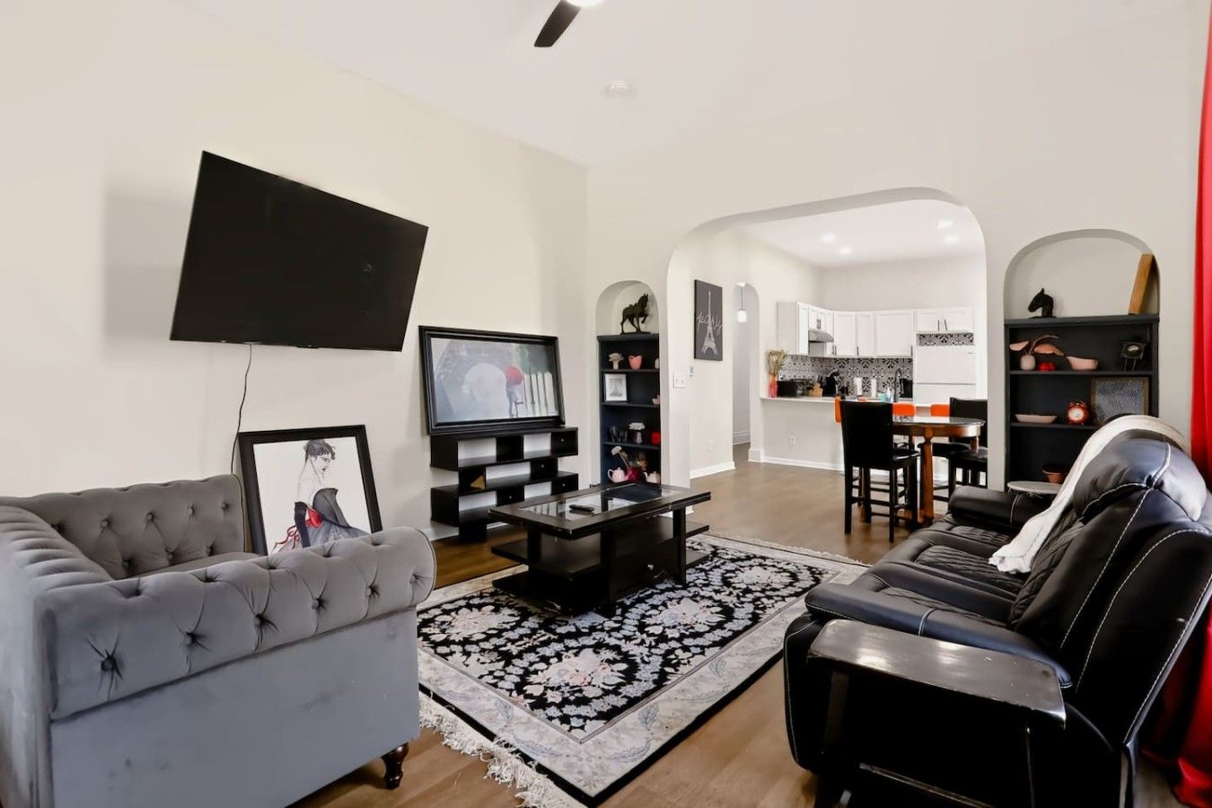 A modern living room with a grey sofa, black leather chair, and a flat-screen TV.