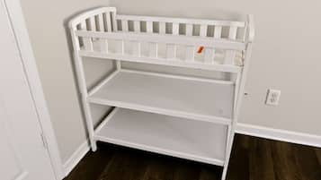 A white, three-tiered, white-framed storage unit against a wall with a power outlet.