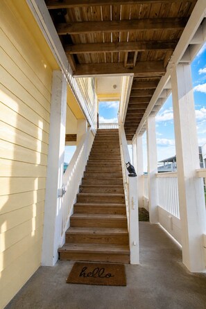 A wooden staircase leading to a covered porch with a 'hello' mat at the bottom. - Huge 5BR w/ Ocean View & Fire Pit (Port Bolivar)