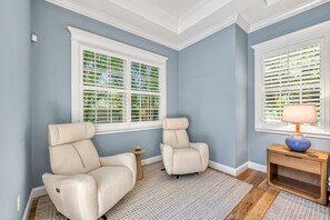 A room with two beige armchairs, a small wooden side table, a blue lamp, and a patterned rug. - Casa De La Cascada | Heated Pool with Grotto, Outdoor Kitchen, Steps to Hillview District (Sarasota)