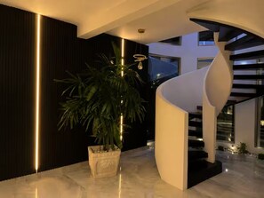 A modern interior with a curved staircase, a potted plant, and a minimalist design.
