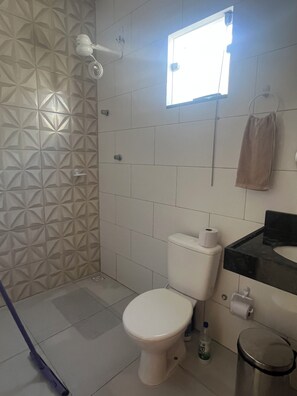 A bathroom with a toilet, a sink, a towel hanging on the wall, and a shower area.