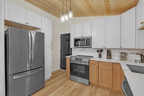 A modern kitchen with stainless steel appliances, wooden cabinets, and a marble countertop. - EV Charger-Renovated-9 Mins to Mercedes-Movie Room (Atlanta)