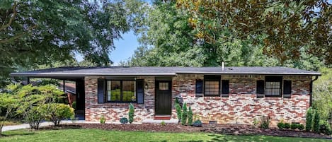 A two-story house with a brick exterior, a front porch, and a well-maintained lawn.