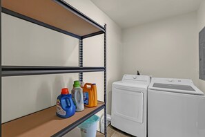 A laundry room with a metal shelving unit, a washing machine, and a dryer. - EV Charger-Renovated-9 Mins to Mercedes-Movie Room (Atlanta)