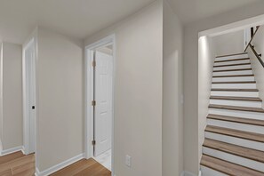 Un corridoio con una porta bianca e una scala in legno.