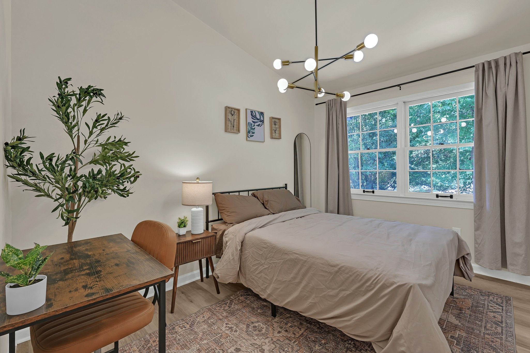 Une chambre à coucher avec un lit, une table de chevet, une lampe, une plante en pot et une fenêtre avec des rideaux.