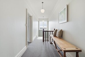 A hallway with a bench, a door, a light fixture, and a window. - Ethelea Retreat – 2 Bedroom – Walk to Restaurant Precinct (North Hobart)