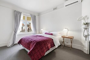 A bedroom with a bed, a nightstand, a lamp, and a potted orchid. - Ethelea Retreat – 2 Bedroom – Walk to Restaurant Precinct (North Hobart)