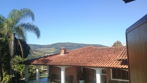 A house with a red-tiled roof, a brick chimney, and a view of a hilly landscape. - Vacation home in Serra Negra, upscale and very quiet neighborhood. (Serra Negra)