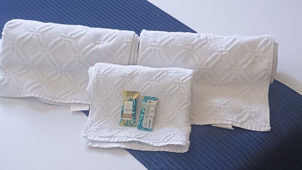 A neatly made bed with white linens and two pillows, a blue bedspread, and a small toiletry bag on the bed. - Vacation home in Serra Negra, upscale and very quiet neighborhood. (Serra Negra)
