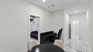 A modern interior with a dining table, chairs, a sofa, and a TV stand.