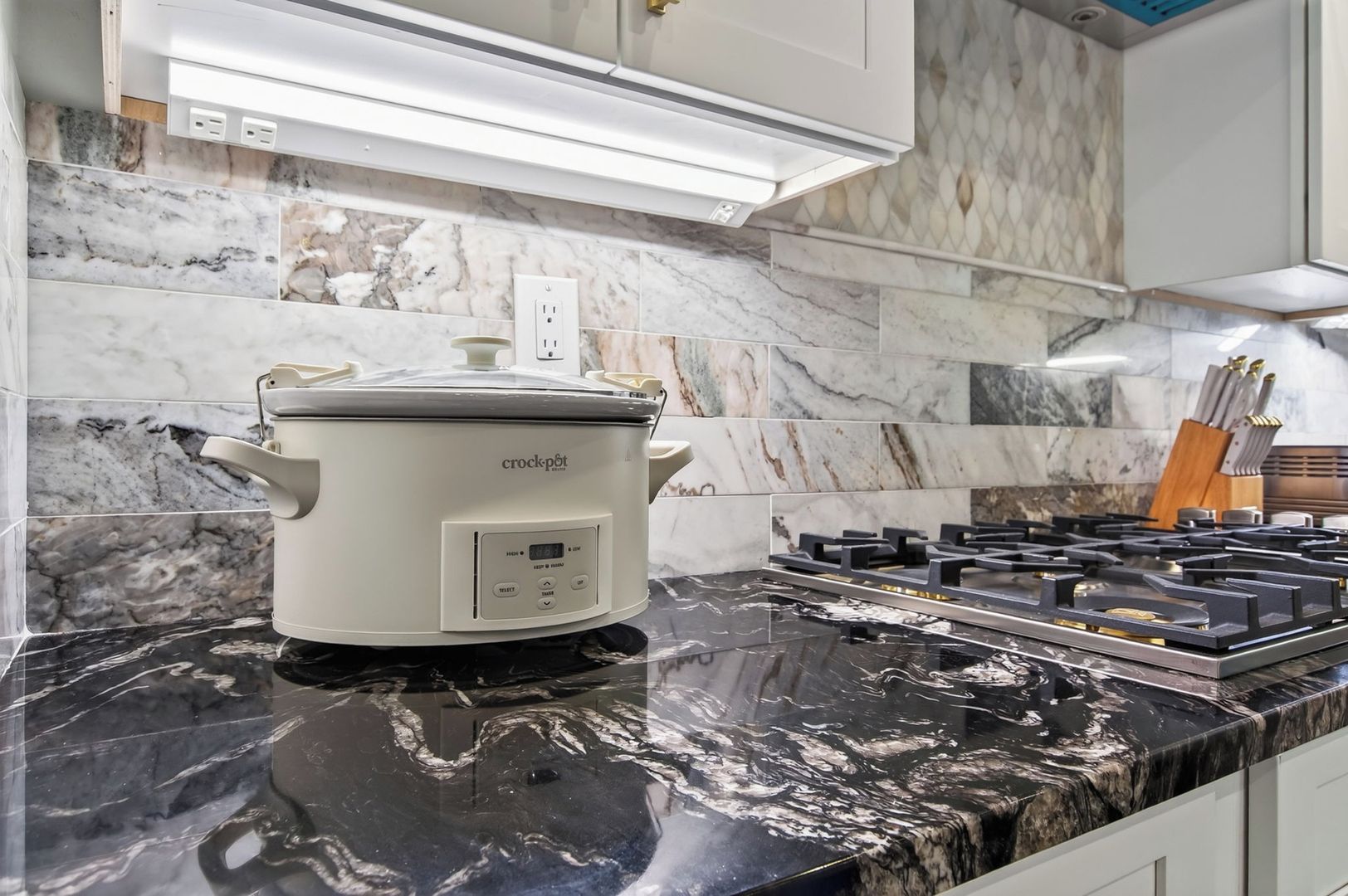 Una cucina con una pentola da cottura bianca, un piano cottura a gas e piastrelle in marmo.