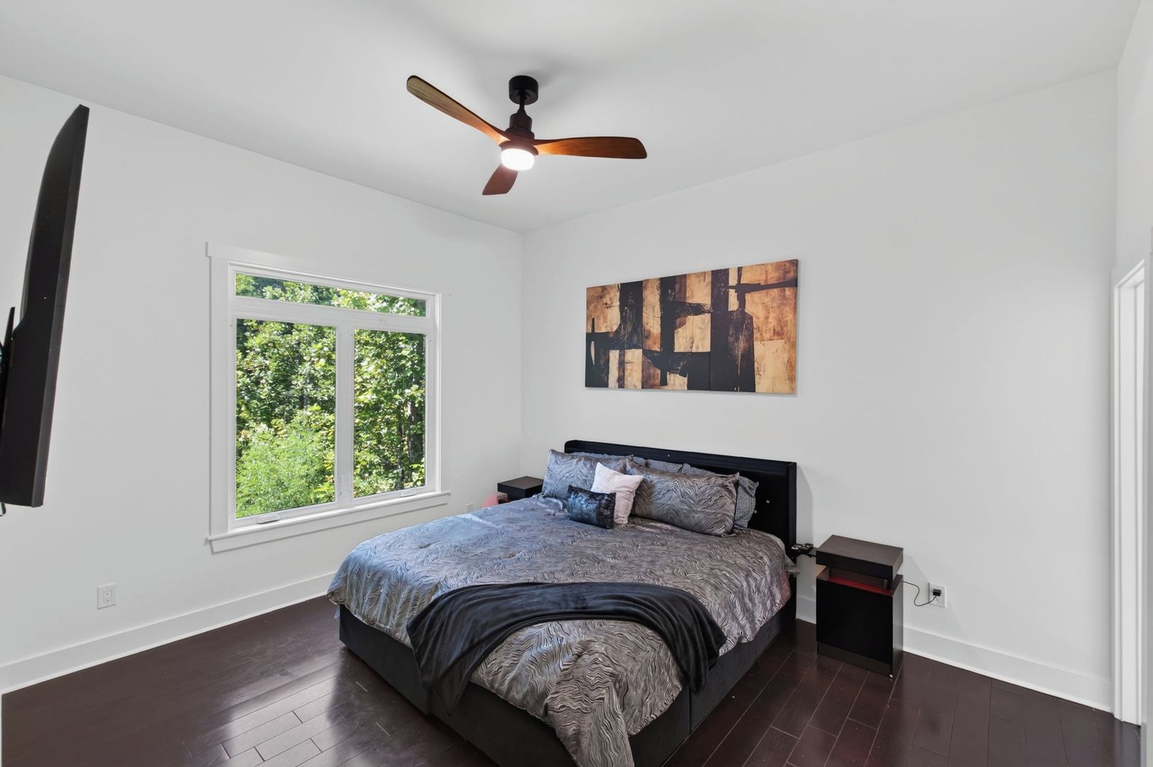 Una camera da letto con un letto, una ventola a soffitto, una finestra e un'opera d'arte appesa al muro.