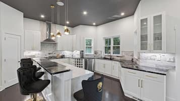 A modern kitchen with a large island, white cabinetry, and pendant lighting.