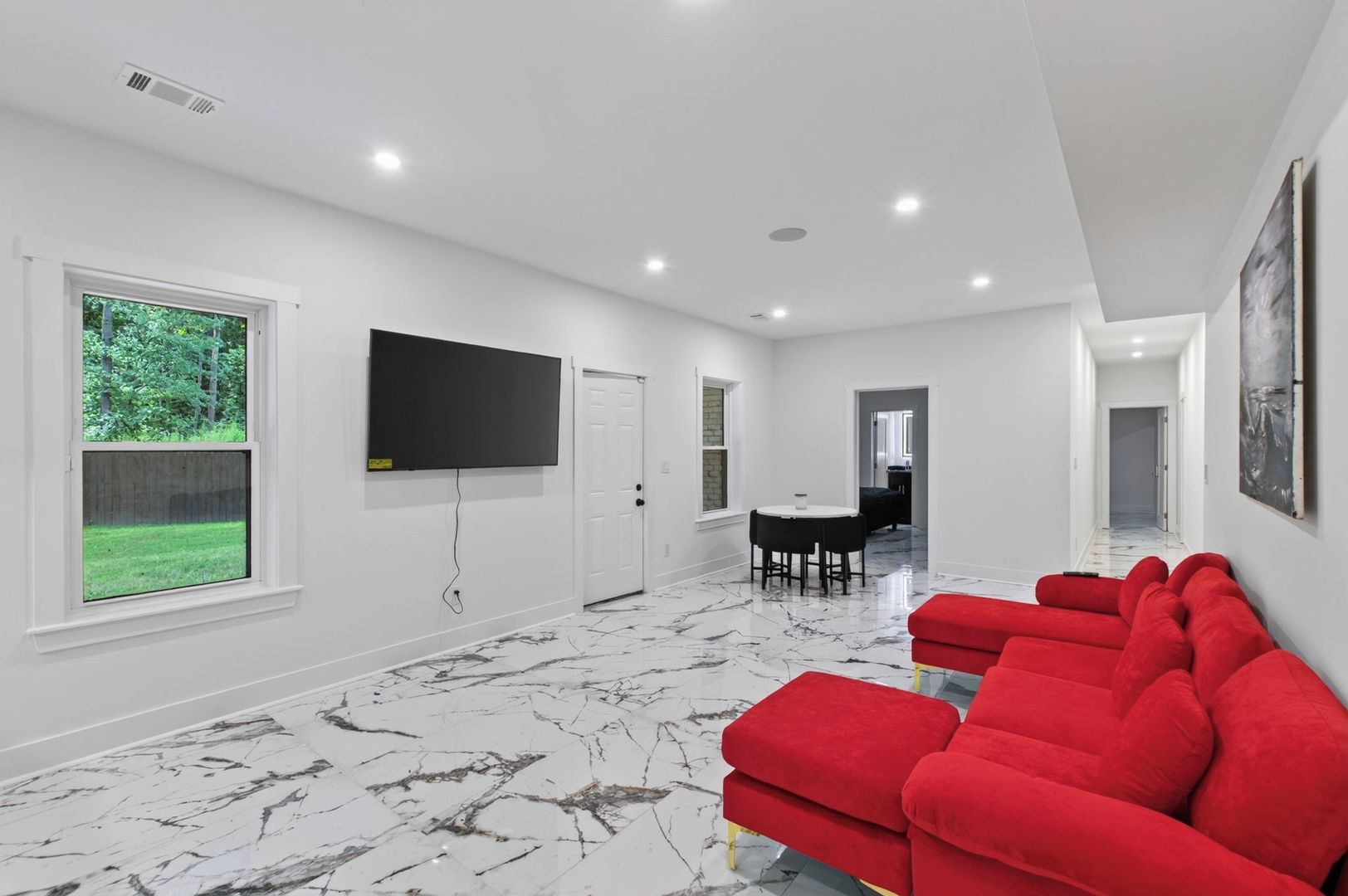 A modern interior with a large flat-screen TV, a dining area, and a red sofa.