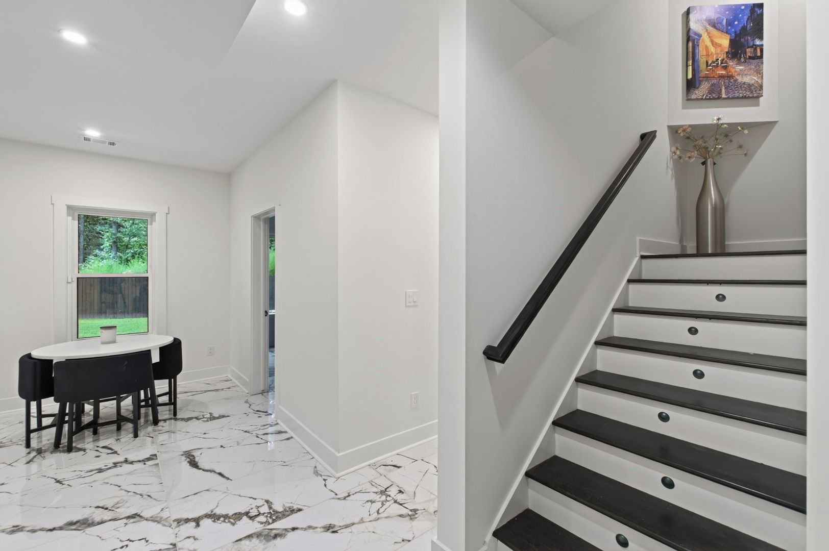 A modern interior with a marble floor, a dining area with a table and chairs, and a staircase with a metal railing.