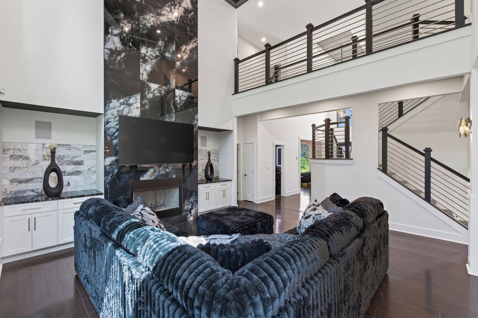 Un salon spacieux avec un grand canapé d’angle, une cheminée et un plafond haut.