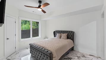 A bedroom with a bed, a ceiling fan, a window, and a door.