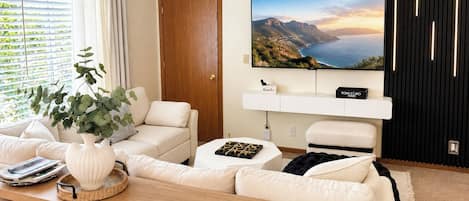 Una sala de estar moderna con un sofá, una mesa de centro y un televisor montado en la pared.