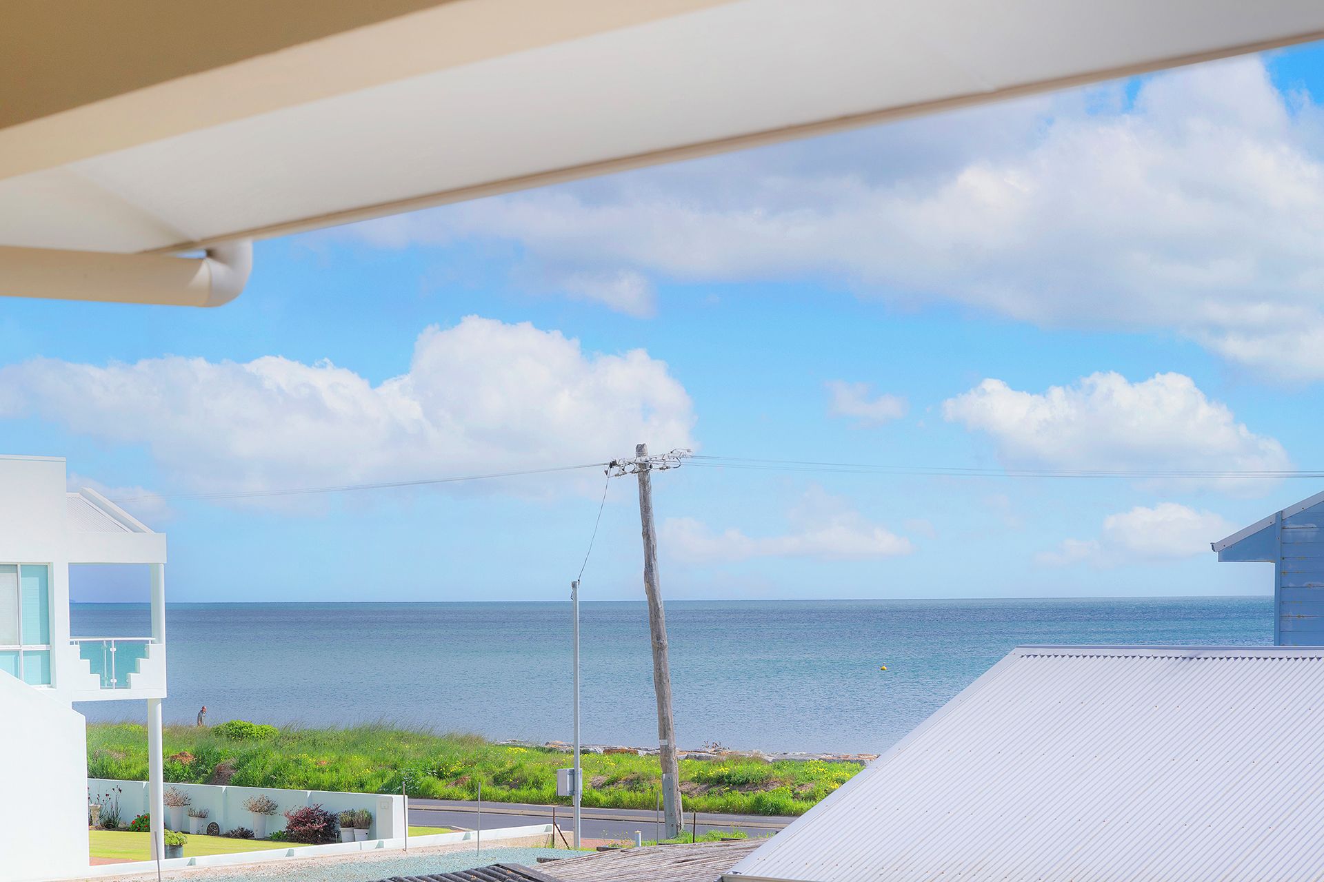 Blick auf die Küste bei klarem Himmel, ein Gewässer und ein weißes Gebäude mit einem Balkon.