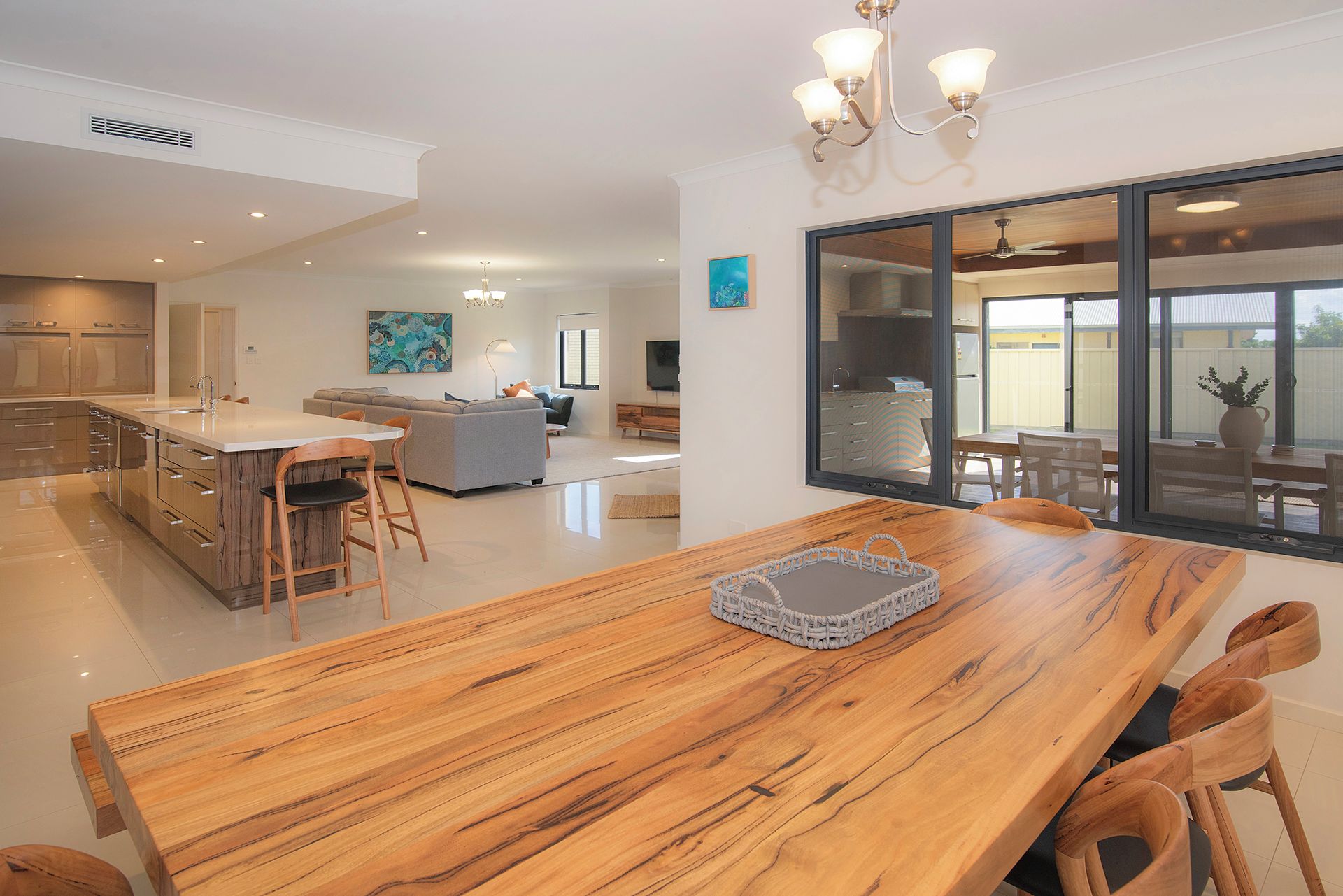 A spacious kitchen with modern appliances, a dining area with a wooden table and chairs, and a large window offering a view of the outdoors.