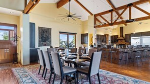 A spacious dining area with a high ceiling and exposed beams, a large window, and a view of the kitchen. - The Villa at Ambyth Estate by Avantstay Pool + Hot Tub + Snooker 42-acre Organic Vineyard (Templeton)