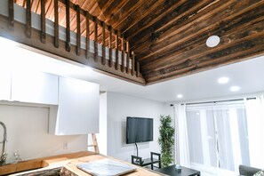 Eine moderne Küche mit Holzboden, einem Essbereich mit Tisch und Stühlen sowie einem an der Wand befestigten Flachbildfernseher.