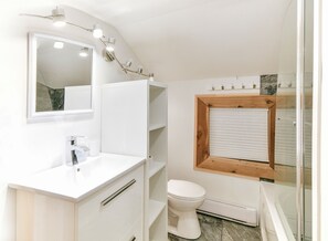 Ein modernes Badezimmer mit einem weißen Waschtisch, einem Spiegel, einer Toilette und einer Duschkabine.
