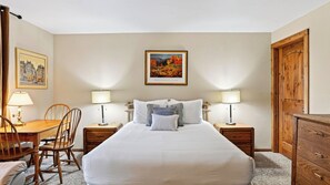 A hotel room with a large bed, two bedside tables with lamps, a wooden chair, a desk, and a wooden wardrobe. - Ski Casa Azul by Avantstay Ski Shuttle + Walk to Main St Shared Hot Tub + Grill (Breckenridge)