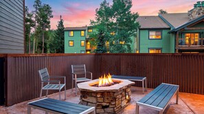 A patio with a stone fire pit, two metal chairs, and a bench. - Ski Casa Azul by Avantstay Ski Shuttle + Walk to Main St Shared Hot Tub + Grill (Breckenridge)
