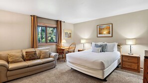 A bedroom with a large bed, a sofa, a desk, and a chair. There is a window with curtains, a lamp, and a framed picture on the wall. - Ski Casa Azul by Avantstay Ski Shuttle + Walk to Main St Shared Hot Tub + Grill (Breckenridge)
