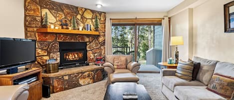 A living room with a stone fireplace, a television, a sofa, and a coffee table.