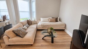 A modern living room with a sectional sofa, a glass coffee table, and a flat-screen TV. - Duplex - Both Units - 2 Kitchens - Privacy - Fenced Yard (Oak Park)
