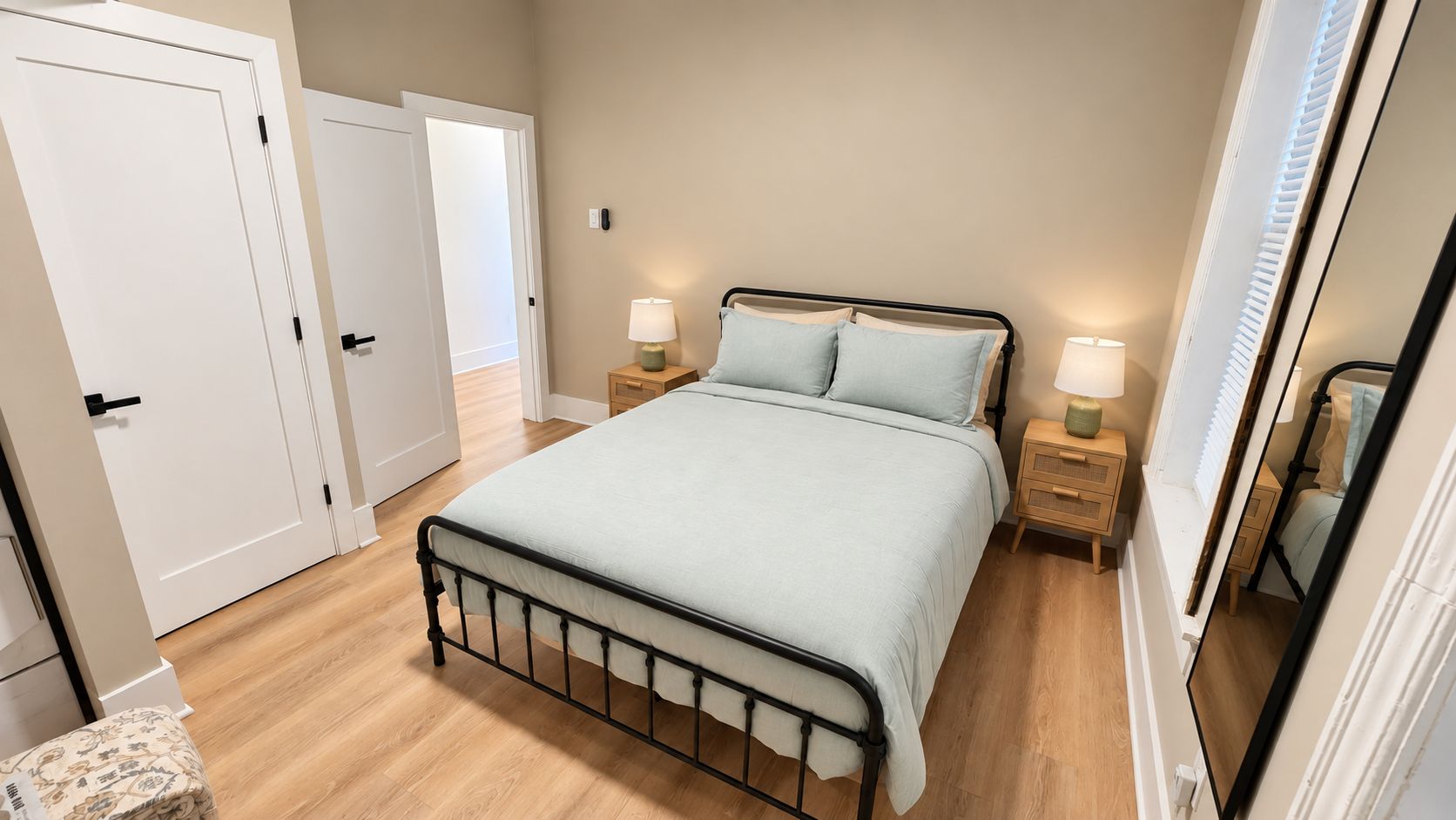 A bedroom with a bed, bedside tables, a mirror, and a door.