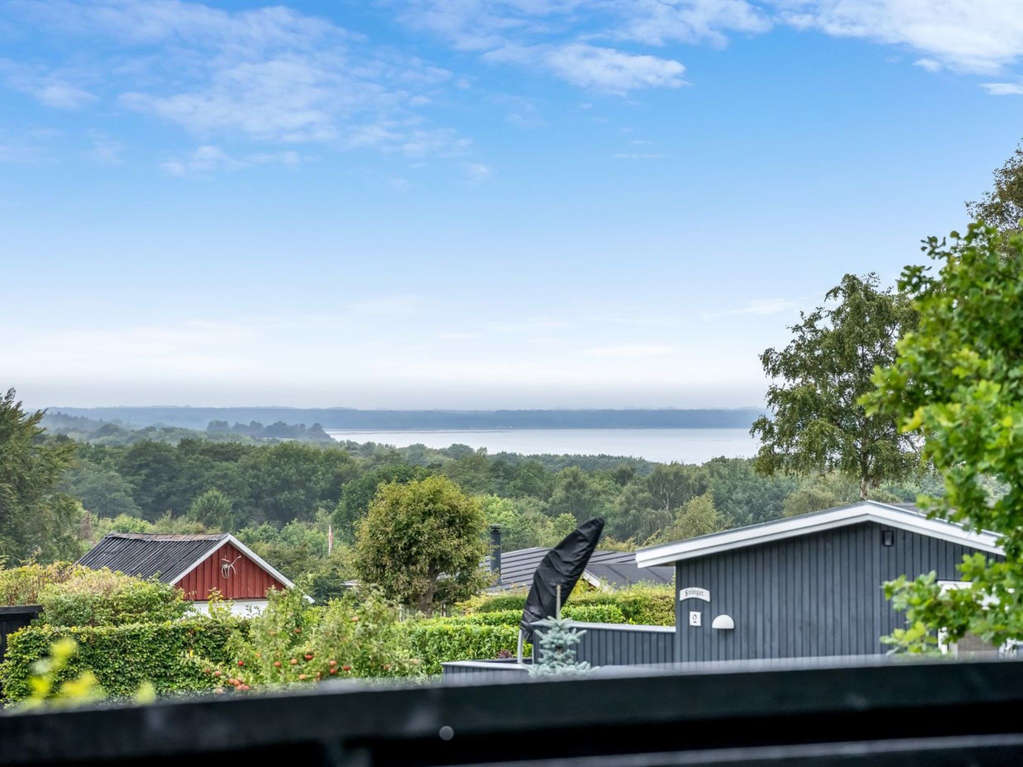 Näkymä kiinteistöön, jossa on punainen rakennus, harmaa rakennelma ja vehreä, vihreä maisema, ja kauempana näkyy vesistö.