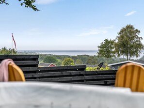 A view from a terrace with a table and chairs, overlooking a body of water and a distant shoreline. - "Thorine" - 800m from the sea by Interhome (Allingåbro)