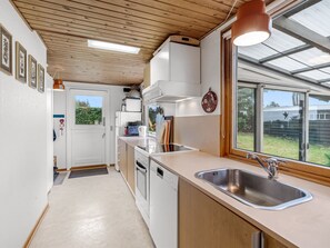 A compact kitchen with white cabinets, a stainless steel sink, and a window providing natural light. - "Thorine" - 800m from the sea by Interhome (Allingåbro)