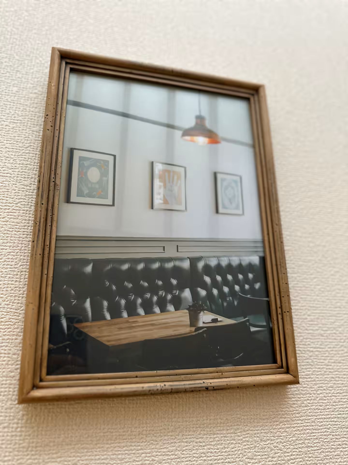 A framed picture of a room with a sofa and a table, and three smaller framed pictures on the wall.