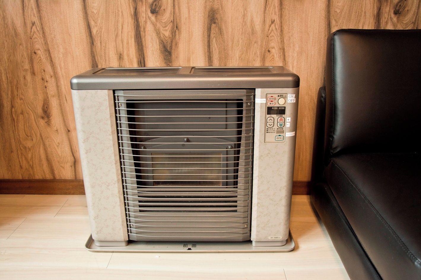 A portable air conditioner unit with a control panel, standing on a wooden floor.