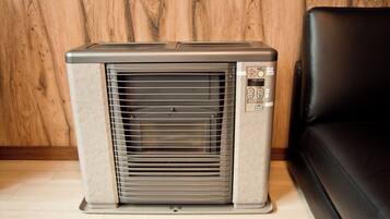 A portable air conditioner unit with a control panel, standing on a wooden floor.