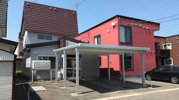 A red building with a covered entrance and a black car parked nearby.